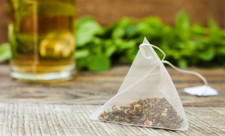 Bolsa de t&eacute; sobre el fondo de la menta y la taza / bolsitas de t&eacute;