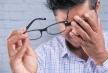 hombre se quita sus gafas y se frota sus ojos por problemas de visión / lagrimal obstruido