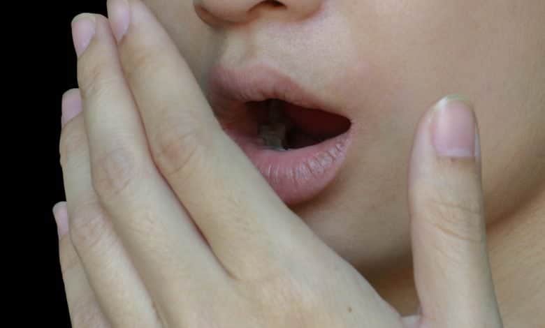 una chica cubri&eacute;ndose la boca por el olor de la boca / eructos