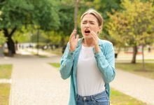 Mujer joven con alergia al aire libre / estornudo