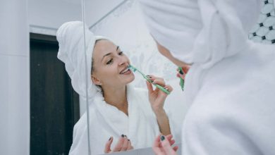Mujer reci&eacute;n salida de la ducha, haciendo limpieza de sus dientes con un cepillo dental / mal aliento