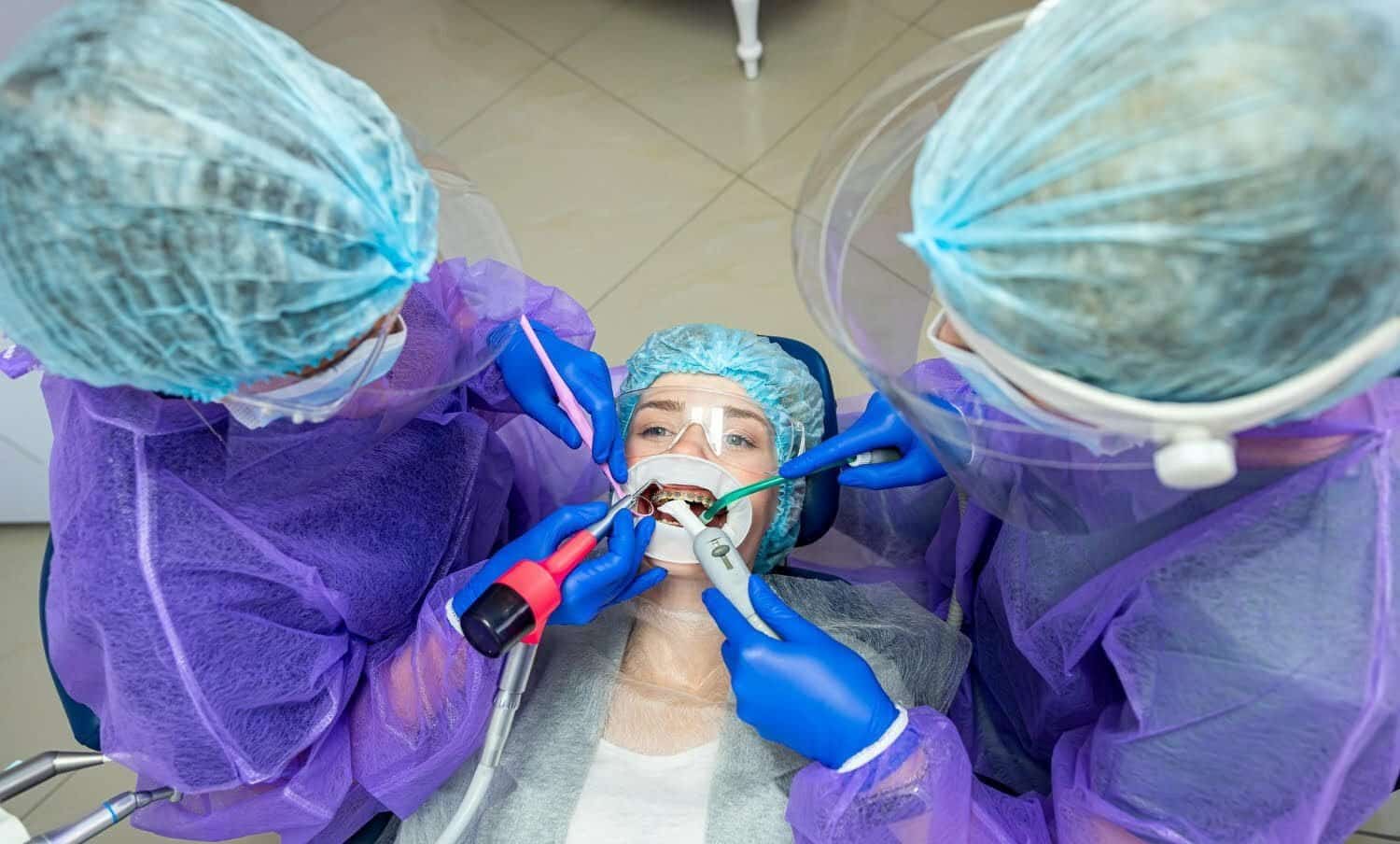 Dentistas realizando cirug&iacute;a bucal a paciente