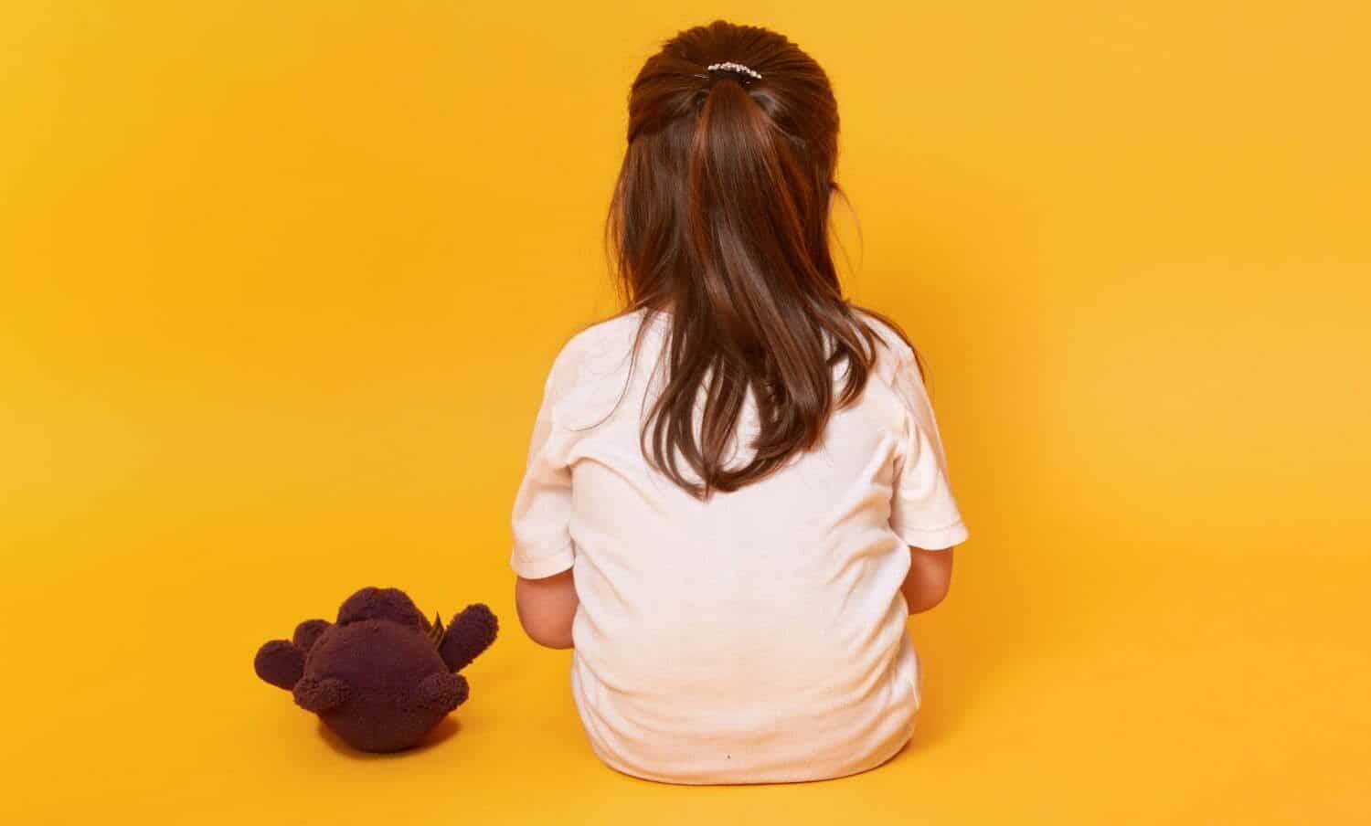 ni&ntilde;a sentada de espalda, con osito de peluche marr&oacute;n, v&iacute;ctima de maltrato infantil bogot&aacute;