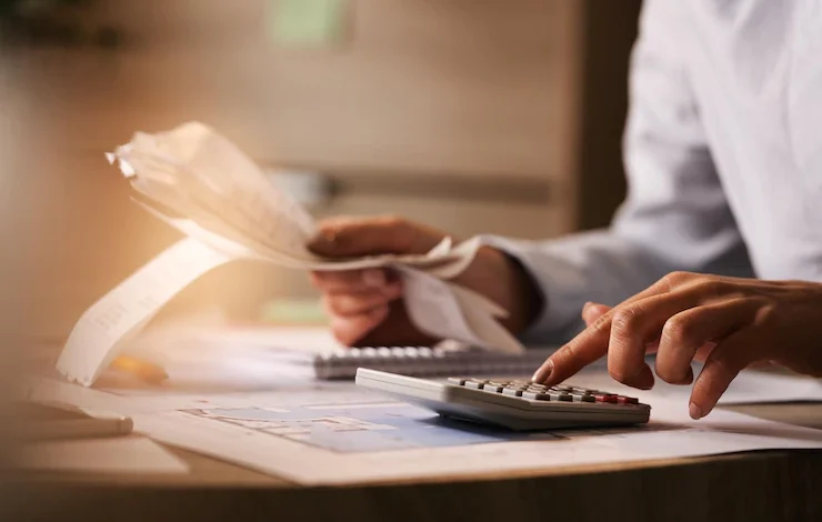 un economista que usa una calculadora mientras revisa las facturas y los impuestos en la oficina, cobros, facturación empresa