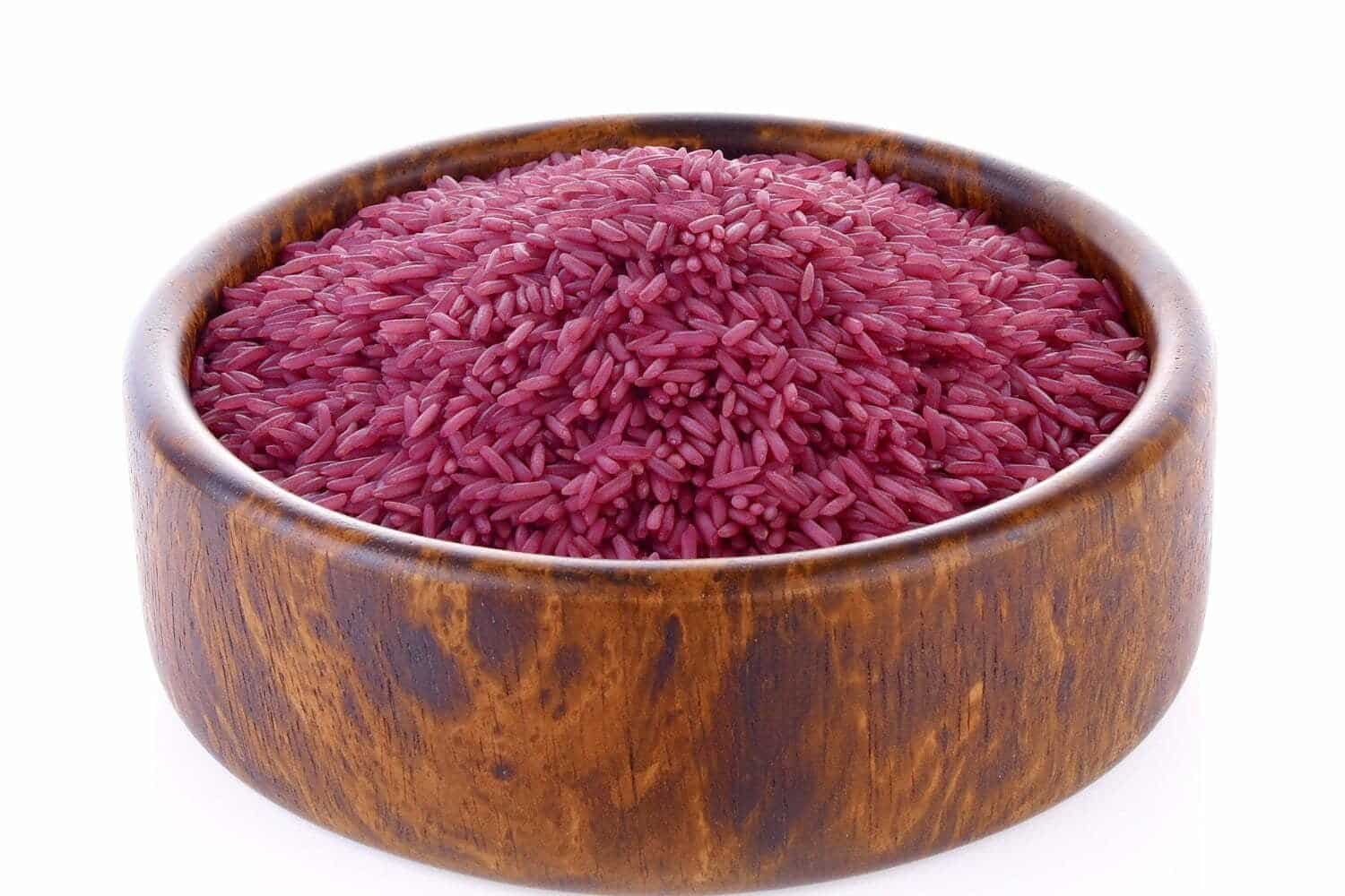 arroz morado dentro de cuenco de madera, sobre fondo blanco