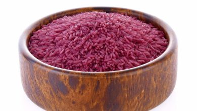 arroz morado dentro de cuenco de madera, sobre fondo blanco