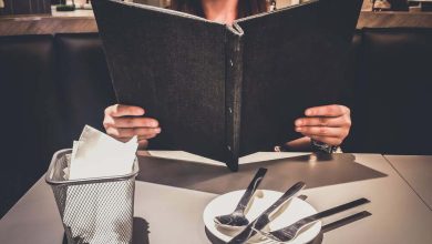 joven Eligiendo Mirar desde un Men&uacute; de Restaurante decidiendo qu&eacute; pedir / restaurante palomas
