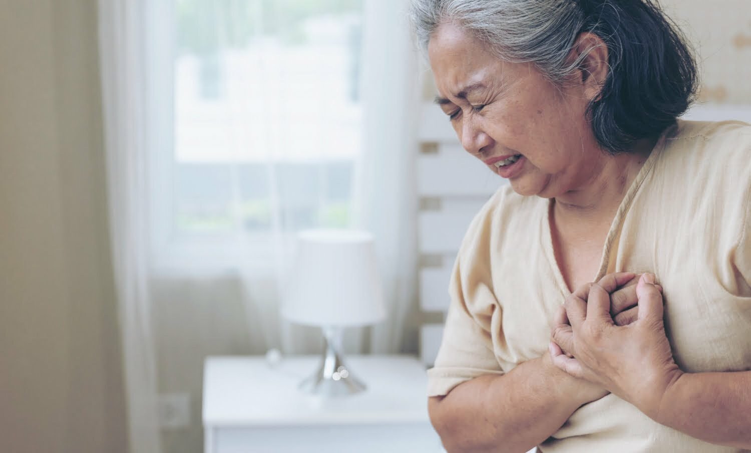 mujer mayor tocando su corazón por dolor a causa de un infarto