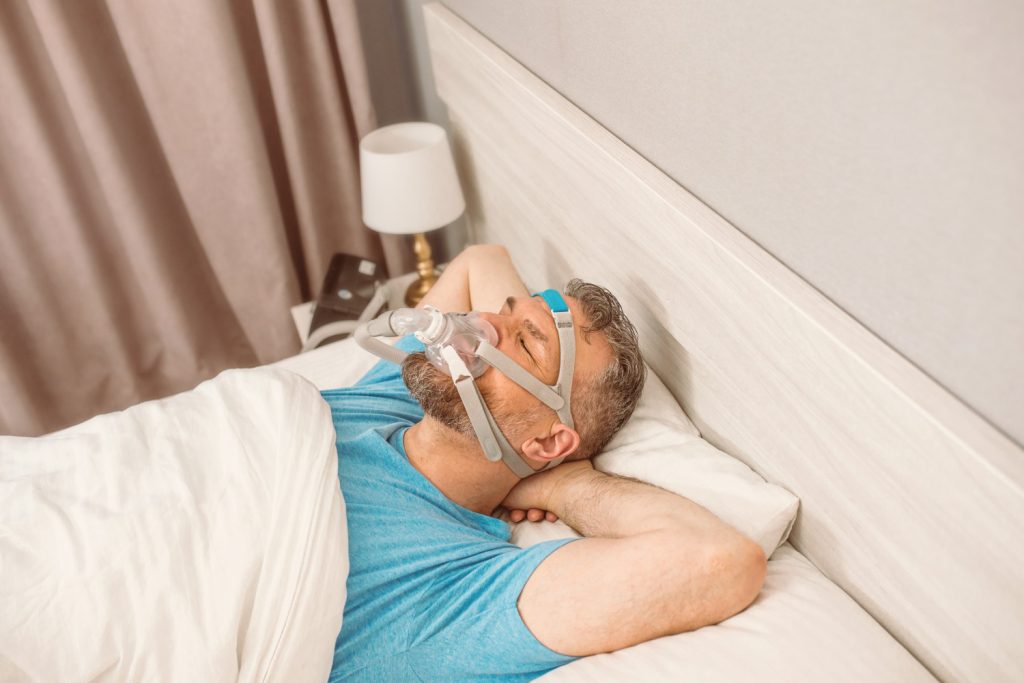 hombre durmiendo con m&aacute;scara respiratoria porque sufre de apnea del sue&ntilde;o