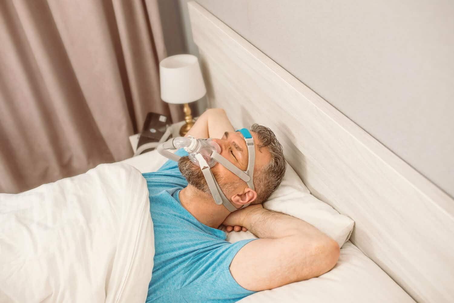 hombre durmiendo con m&aacute;scara respiratoria porque sufre de apnea del sue&ntilde;o