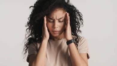 mujer tocando su cabeza por causa de migra&ntilde;a / ardor en la cabeza