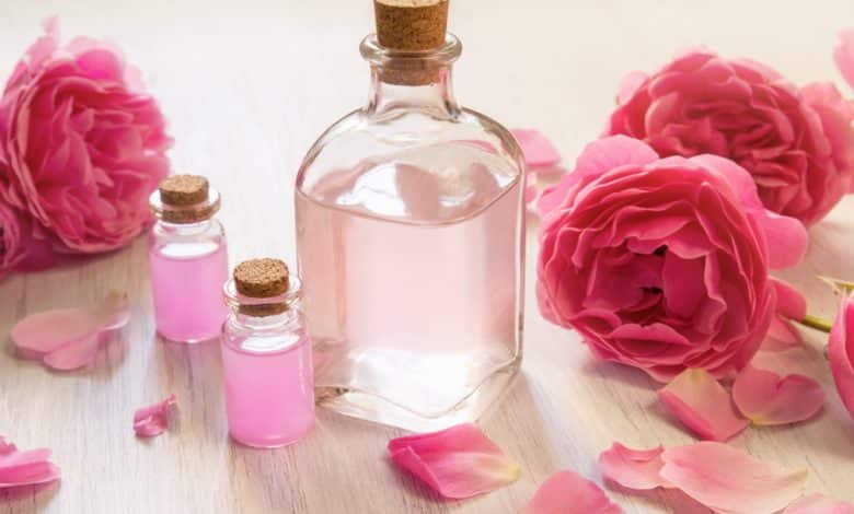 Aceite de rosa en botellas de vidrio con flores rosas / agua de rosas