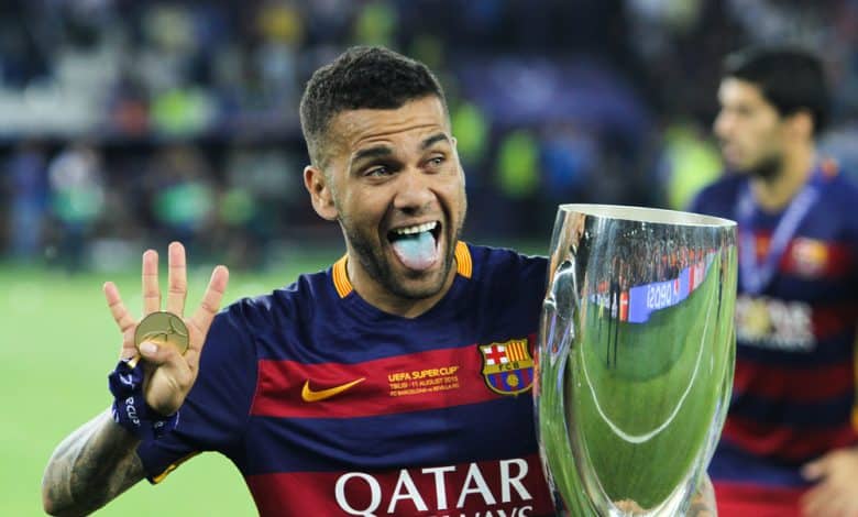 dani alves posa con el uniforme del FC barcelona y una copa