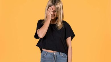 Mujer joven con actitudes de timidez, tapando su cara