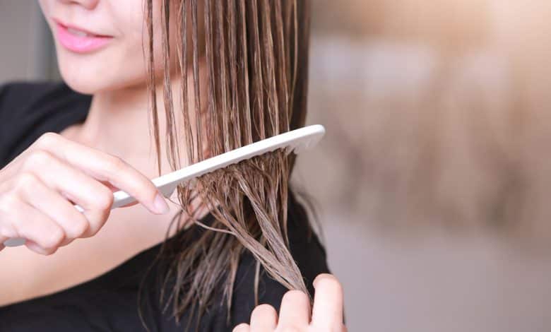 Mujer con un peine en la mano en el vestidor / peinados con efecto mojado