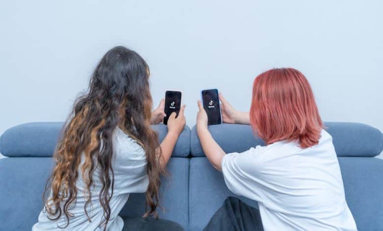 Dos adolescentes con tel&eacute;fonos en las manos sentadas en casa en la cama / retos virales