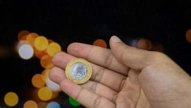 Foto sosteniendo una moneda de dinero brasile&ntilde;o en un fondo de luces borrosas
