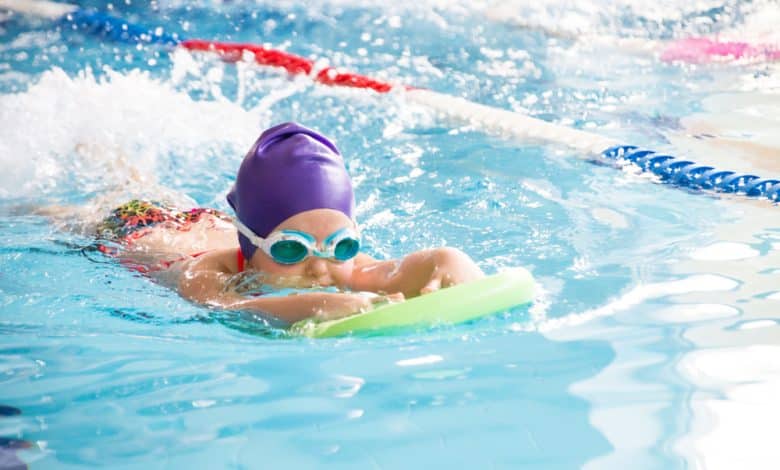 ni&ntilde;a peque&ntilde;a nadando en piscina azul / trastorno TDAH
