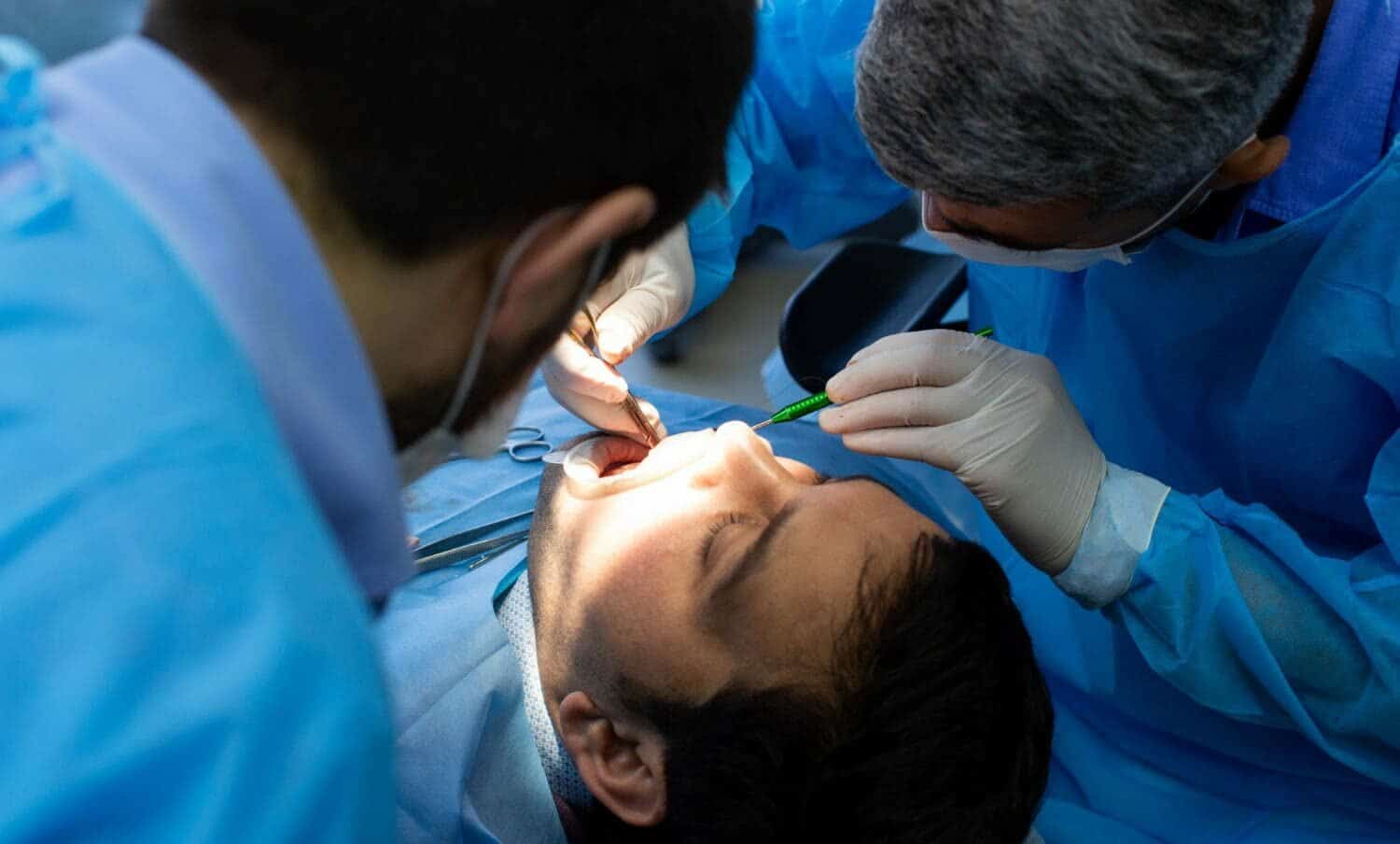 Odont&oacute;logo realizando cirug&iacute;a oral a paciente cuerpo joven