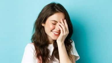 bella joven que se r&iacute;e y ruboriza, cubriendo la cara / eritrofobia