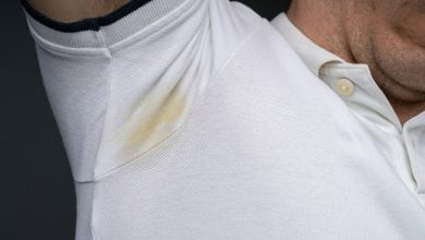 Close-up de la axila del hombre sudando mucho contra un fondo gris / manchas de sudor