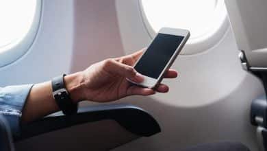 Mujer con la mano usando un smartphone en avi&oacute;n / modo avi&oacute;n