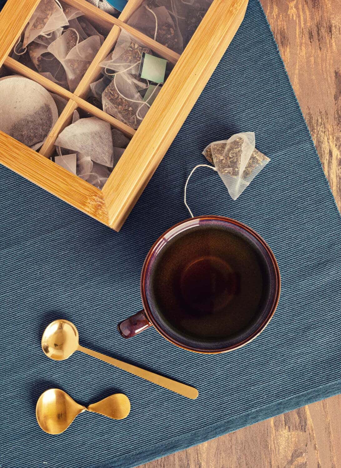 Tetera y taza de t&eacute; con bolsitas de t&eacute; de hierbas que contienen cafe&iacute;na