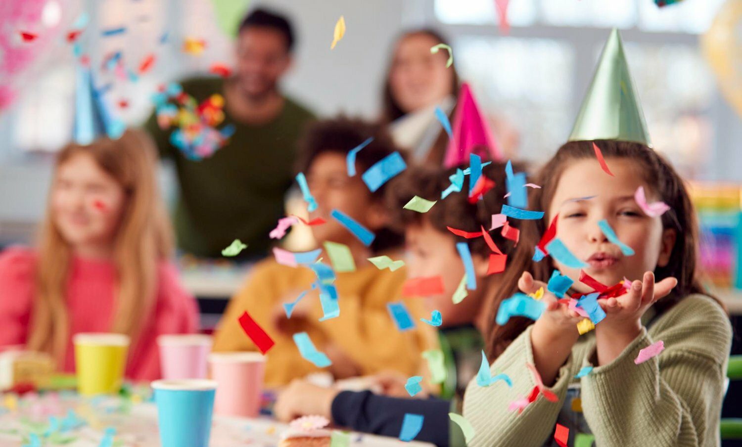 niña en fiesta para niños soplando confeti / septiembre