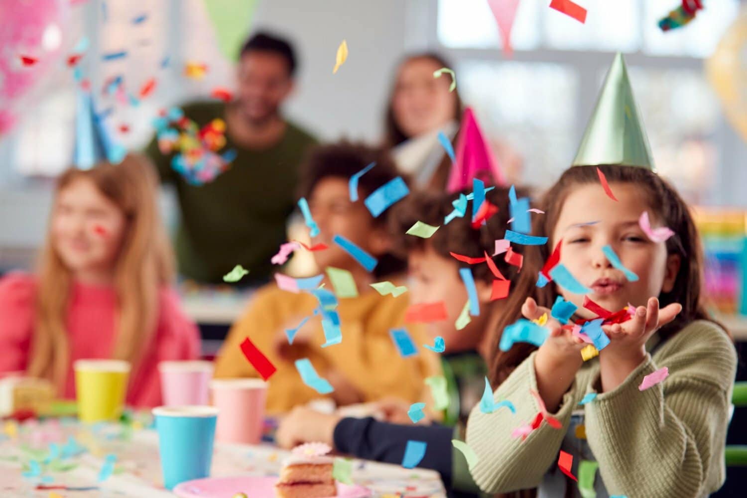 ni&ntilde;a en fiesta para ni&ntilde;os soplando confeti