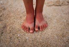 pies de ni&ntilde;a sobre la arena insolaci&oacute;n