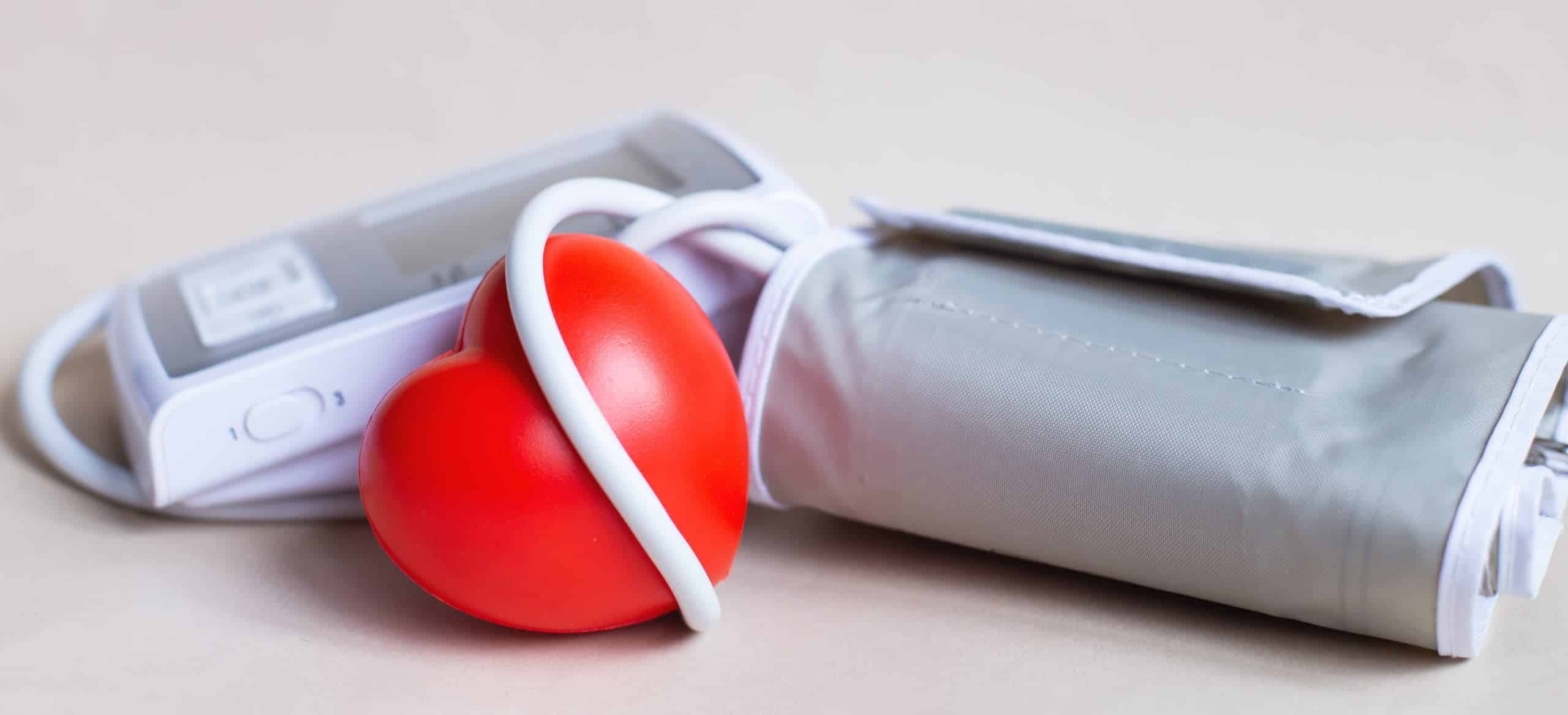 Foto coraz&oacute;n rojo y ton&oacute;metro electr&oacute;nico blanco aislado sobre fondo beige hipertenso / Efectos del ruido del tr&aacute;fico en la gente