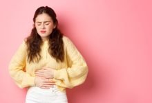 mujer joven con dolor en su estómago por aparición de gastritis período menstrual osteopatía licencia menstrual