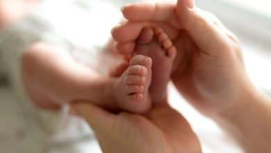 Pies peque&ntilde;os de un beb&eacute; reci&eacute;n nacido en manos de mam&aacute; / padres primerizos