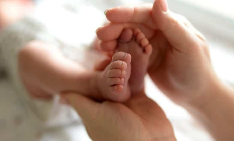 Pies peque&ntilde;os de un beb&eacute; reci&eacute;n nacido en manos de mam&aacute; / padres primerizos