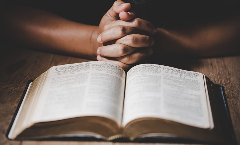 persona orando con las manos empuñadas y una biblia, significado de ¡aleluya!