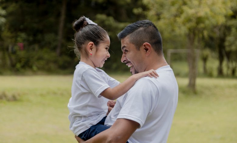 Padre hispano abrazando a su pequeña hija en el parque / día del padre