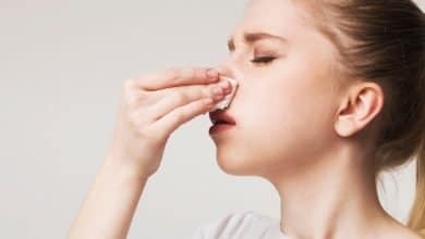 Mujer joven que sufre hemorragia nasal / sangra la nariz