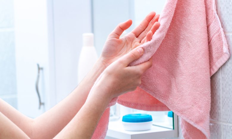 Persona que usa toalla para limpiar las manos secas despu&eacute;s de lavarlas en el ba&ntilde;o en casa / toallas de ba&ntilde;o