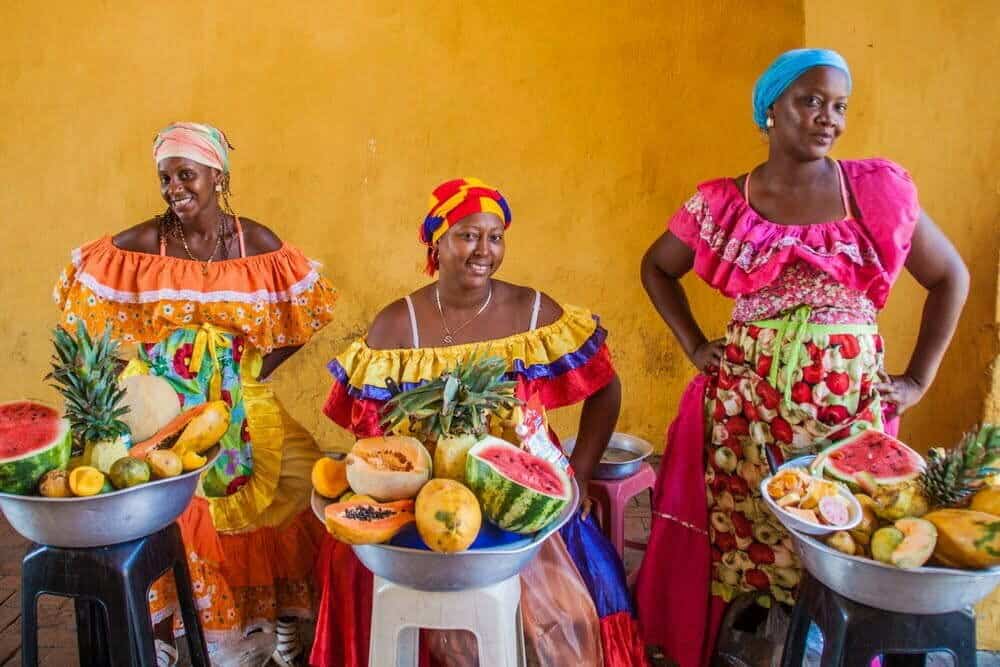 CARTAGENA DE INDIAS, COLOMBIA - 28 DE AGOSTO DE 2015: Mujeres vestidas con trajes tradicionales venden frutas en el centro de Cartagena. / Colombia