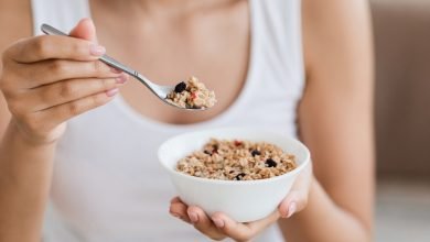 Imagen recortada de una mujer sosteniendo un taz&oacute;n con granola o harina de avena casera / desayuno