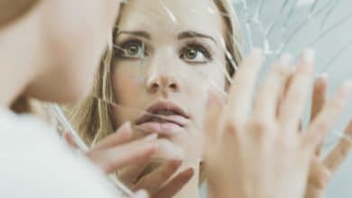 Rostro de mujer esquizofr&eacute;nica reflejado en espejo roto / complejos