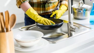Imagen recortada de una mujer lavando una sart&eacute;n en la cocina / olor a huevo