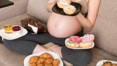 El cierre de una mujer embarazada hambrienta sentada en el sof&aacute; / embarazo