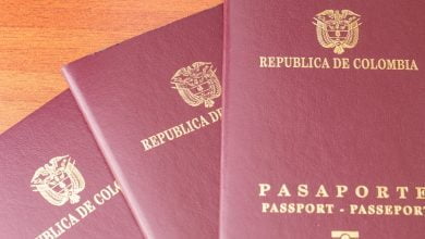 Cierre de tres pasaportes colombianos colgados en una mesa de madera / Leyva Durán - Cancillería