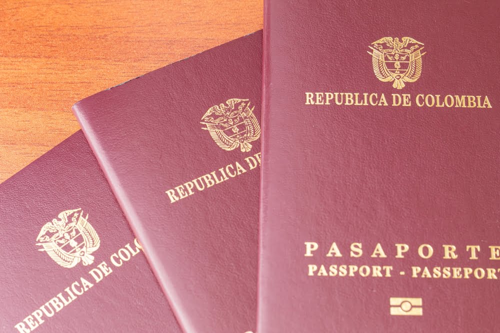 Cierre de tres pasaportes colombianos colgados en una mesa de madera / Leyva Durán - Cancillería